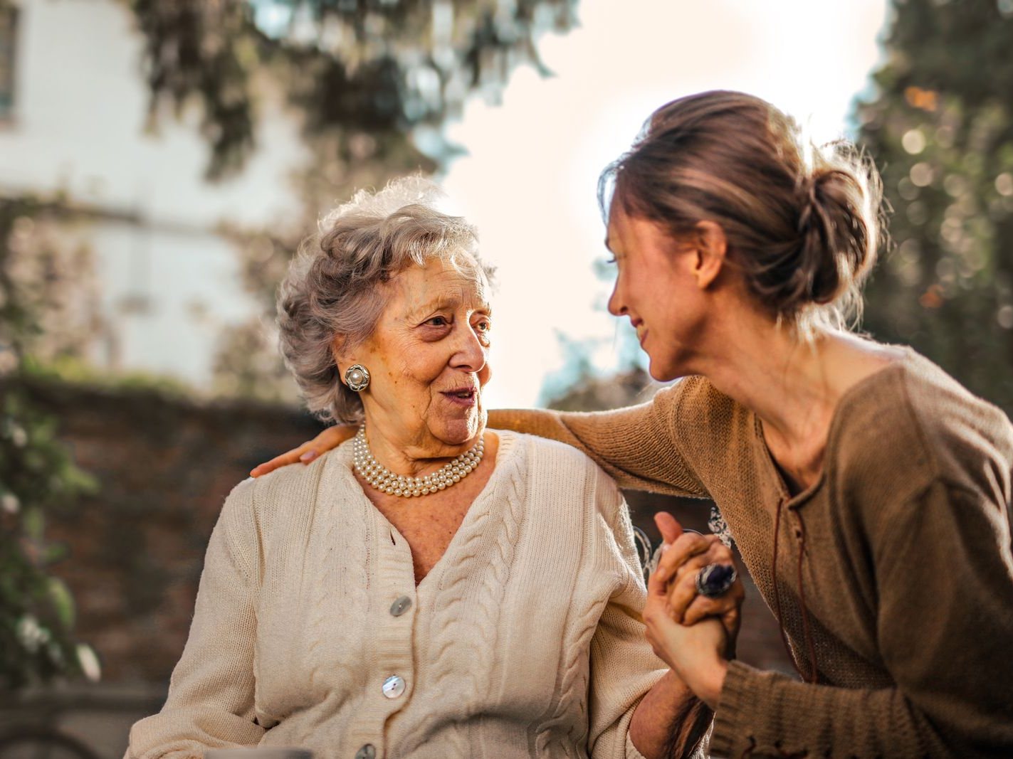 Une jeune femme serre dans ses bras une femme âgée, toutes deux souriantes