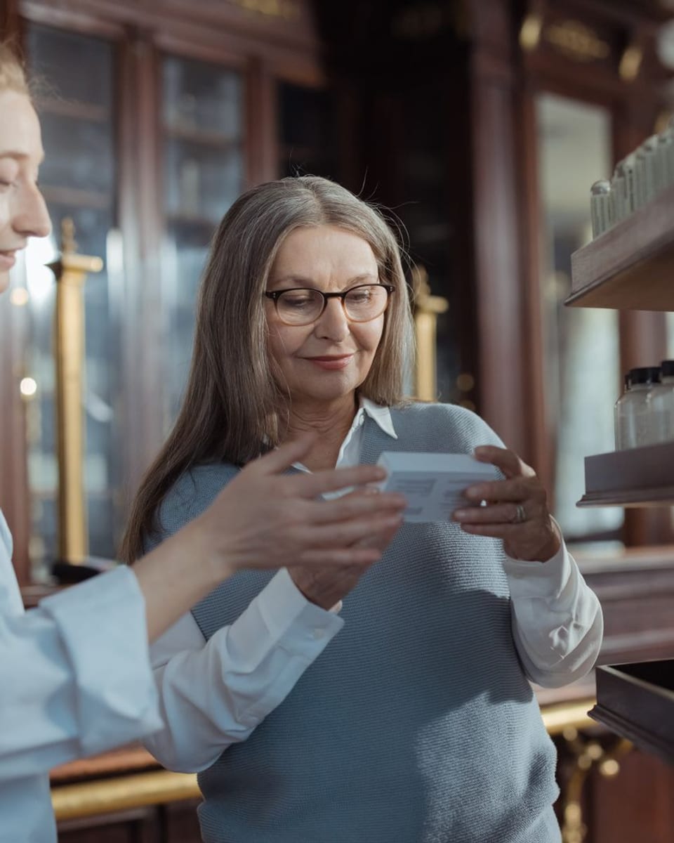 Une pharmacienne présente un produit à une femme âgée dans une pharmacie