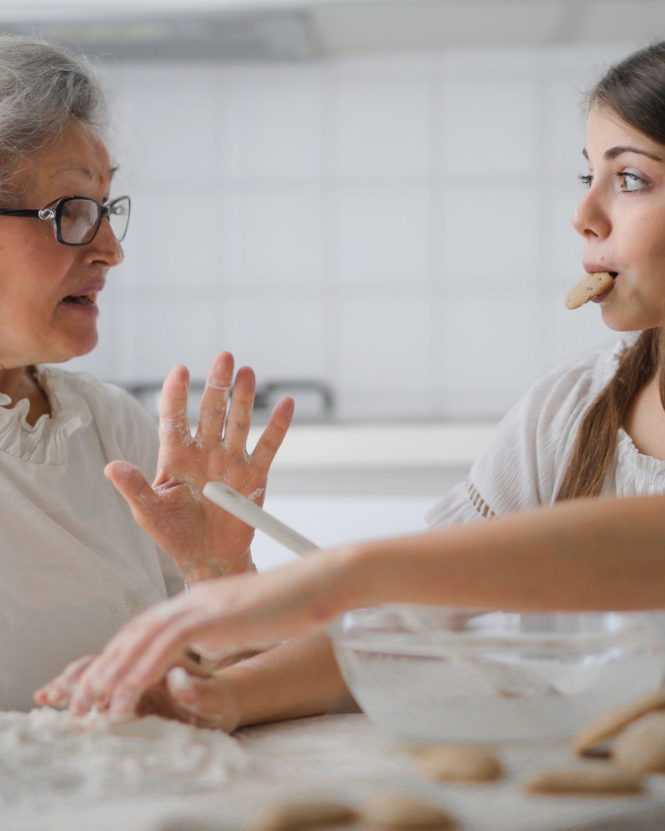 Une femme âgée cuisine chez elle avec une proche plus jeune