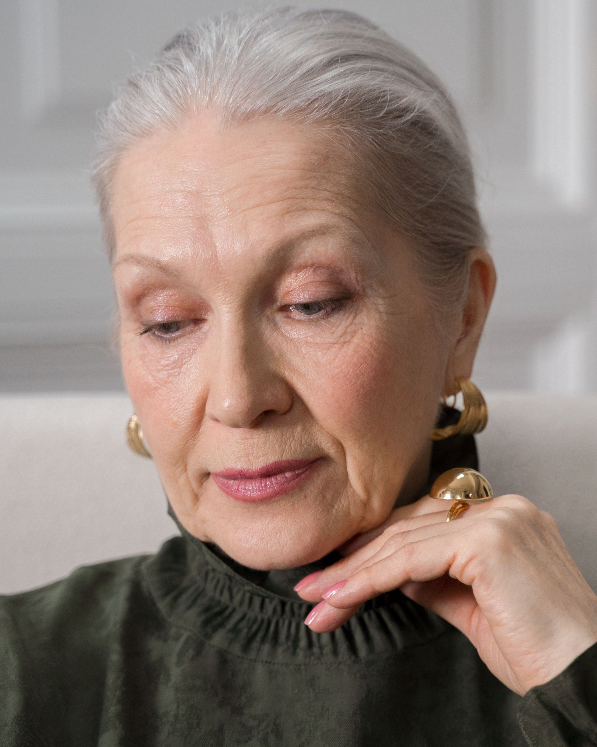 Une femme âgée aux cheveux gris, pensive, la main sous le menton